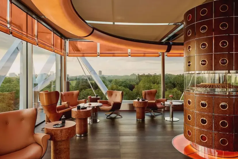 Elegant lounge at The Emory, London, with floor-to-ceiling windows offering views of lush greenery.