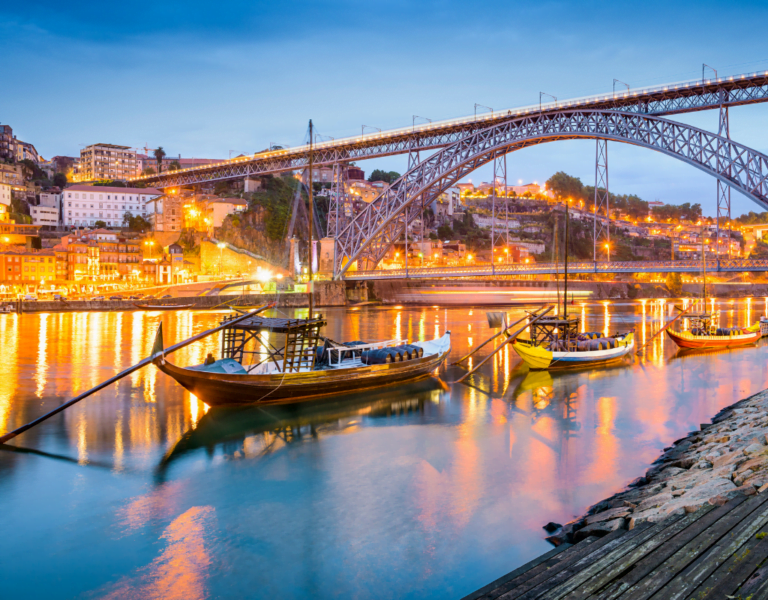 Lisbon at night with historic buildings illuminated along the Tagus River.