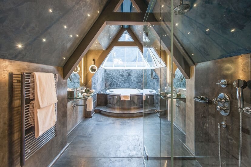 Elegant bathroom at Le Grand Bellevue, featuring a freestanding bathtub, marble finishes, and large windows with views of the Swiss landscape.