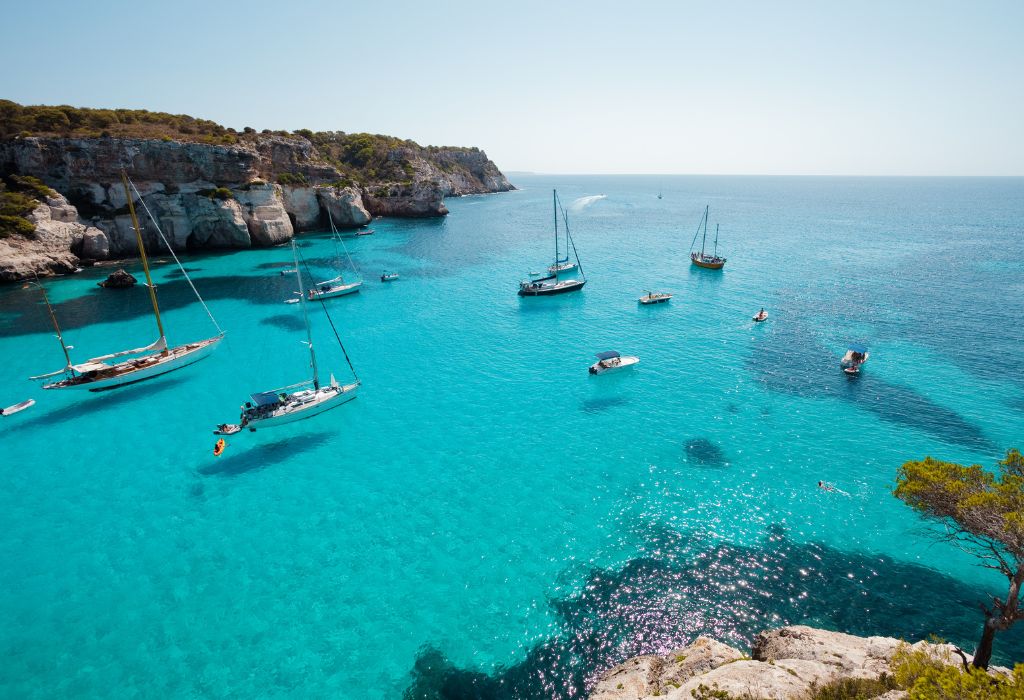 Boats anchored in front of Cala Macarella bay, Menorca, Spain