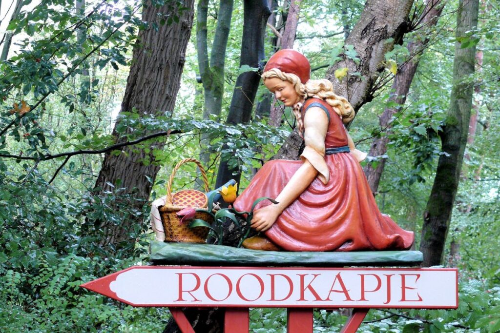 Wooden figure of Little Red Riding Hood in the forest at Efteling Theme Park