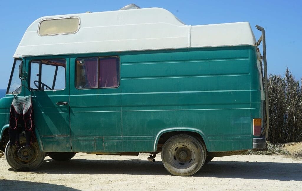 Vintage surfcamper parked on a tranquil beach at dawn in Ericeira, Portugal