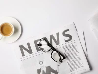 Coffee cup, glasses, and a newspaper with the word "News," symbolizing the latest travel trends and Europe travel news for unique travel experiences.