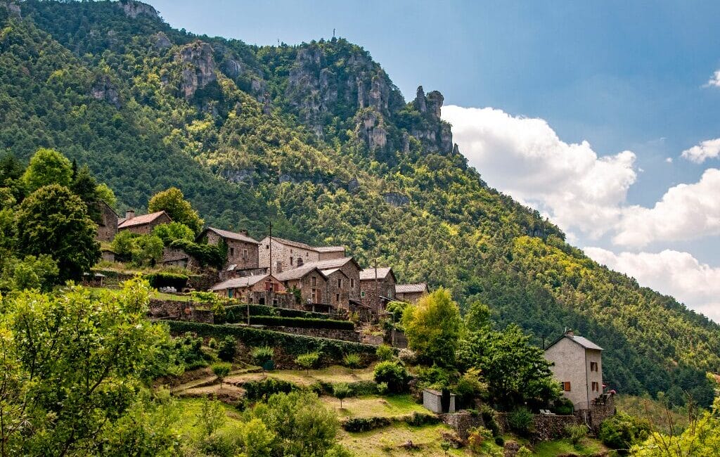 Old village on a hillside with mountains and green meadows in Parc National des Cévennes