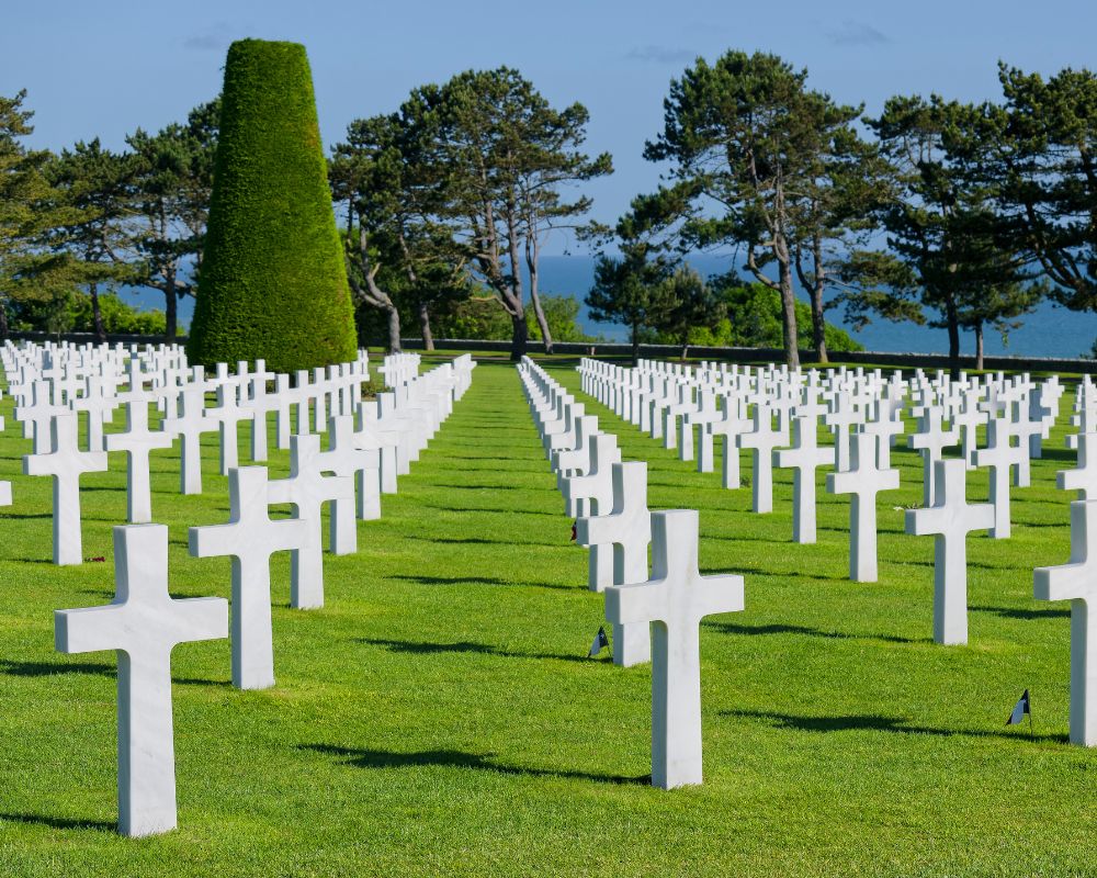 Normandy military cemetery with a large green field and numerous white crosses