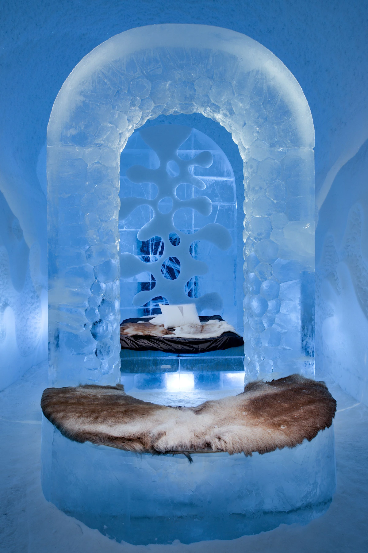 ICEHOTEL Sweden - Interior view of an ice room with intricate ice sculptures and a bed made of ice in Kiruna.