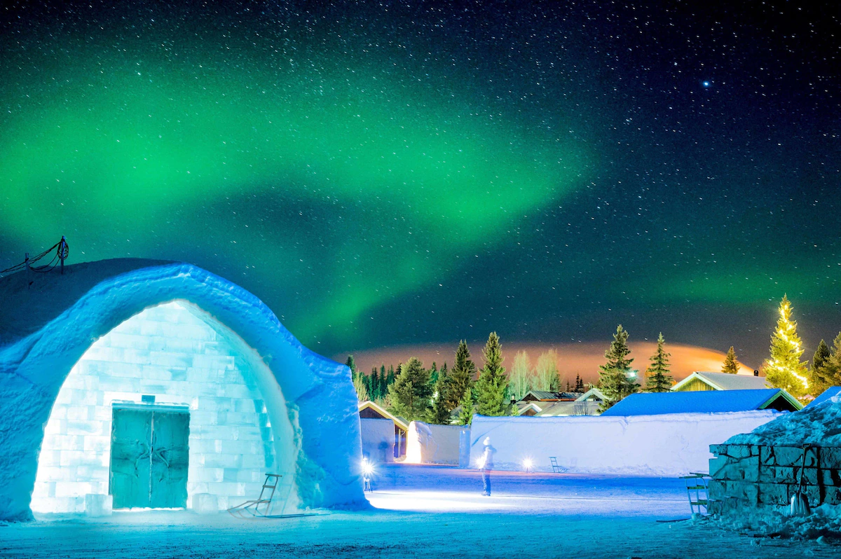 ICEHOTEL Sweden - Northern Lights over ice huts in Kiruna, creating a stunning Arctic night scene