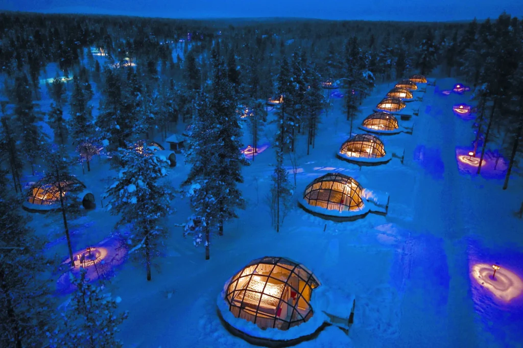 Kakslauttanen Arctic Resort East Village Finland - Exterior view of glass-roofed igloos in snowy landscape, perfect for watching the Arctic night sky.