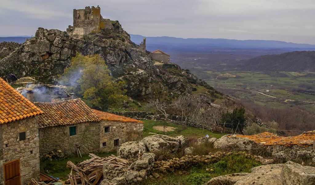 An old village perched on a hill overlooking the vast landscape of Extremadura, Spain.