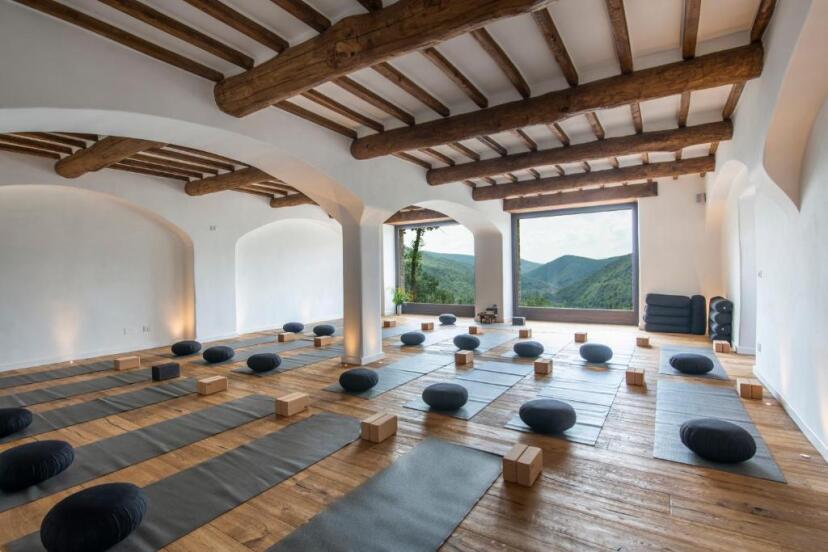 Yoga practice room at Eremito with large windows offering a panoramic view of the surrounding mountains, creating a serene and inspiring environment.