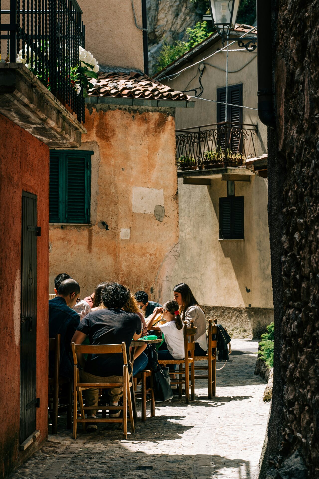 Italian family dining at a table outside their house in an old village, symbolizing cultural differences in individualism vs. collectivism