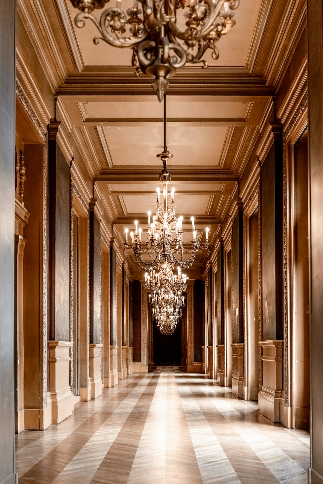 A grand hallway in a castle adorned with impressive chandeliers hanging from the ceiling