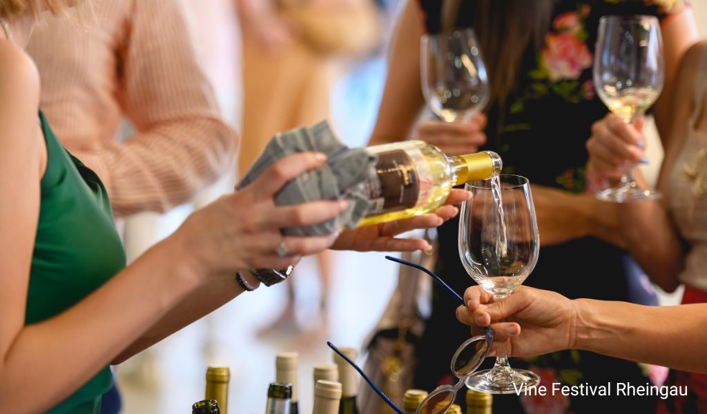 People with wine glasses at Rheingau Wine Festival with a woman pouring wine